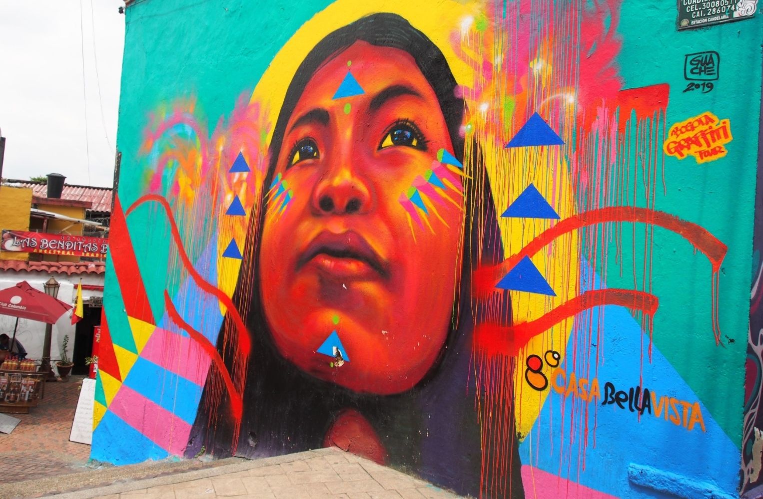 Mural colorido de una mujer con una cabeza grande, destacando su expresión y detalles vibrantes.