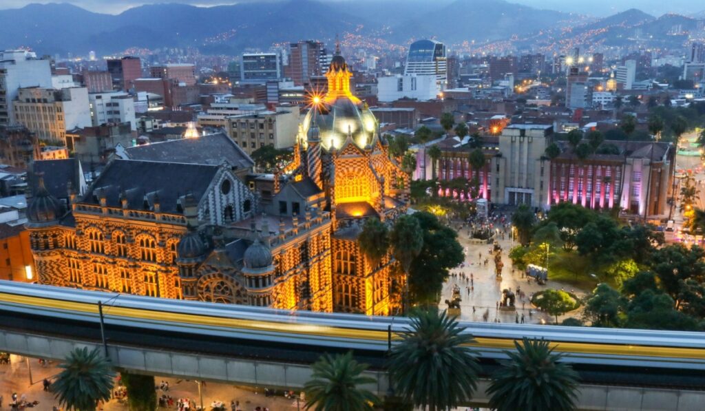Palace of Culture and Plaza Botero in Medellín, Colombia, at night with the subway passing in front.