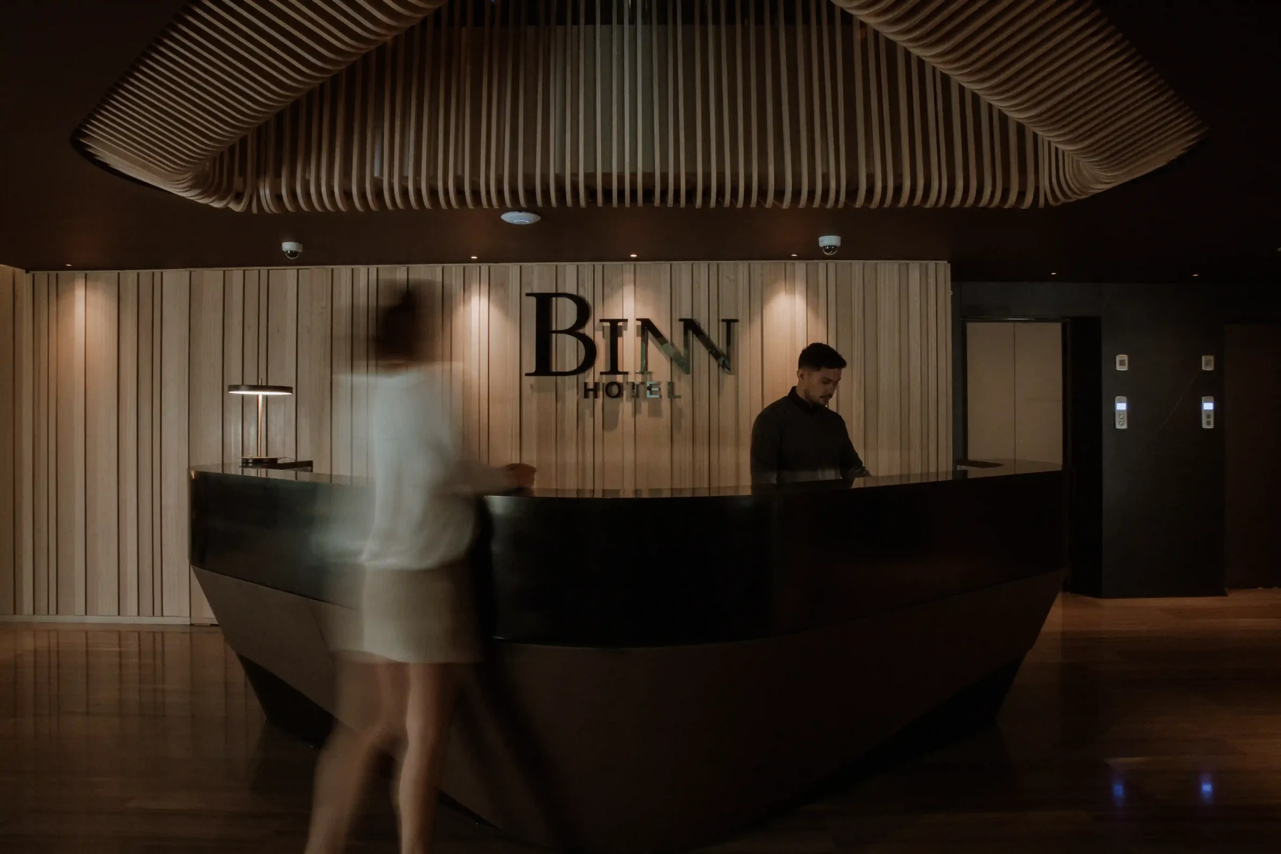 Recepción del lobby de BINN Hotel con huéspedes y techo de madera en El Poblado