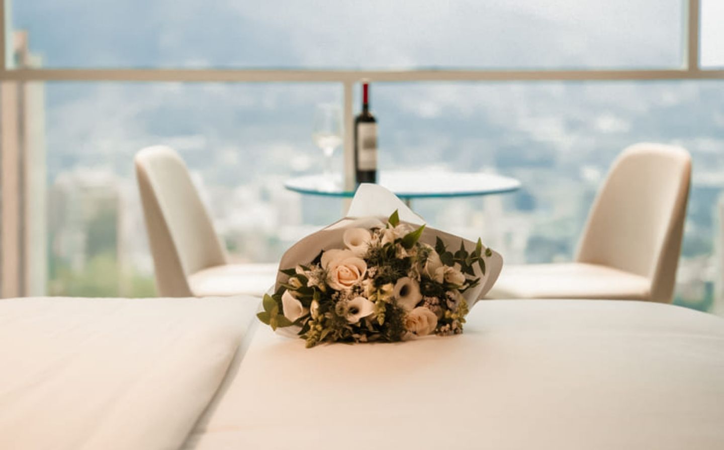 Escapada romántica en Medellín en Binn Hotel con bouquet sobre la cama, vista a la ciudad y ambiente íntimo ideal para parejas.
