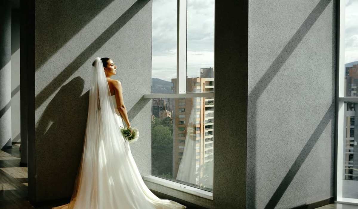 Novia posando junto a un ventanal con vista a la ciudad en el Binn Hotel.