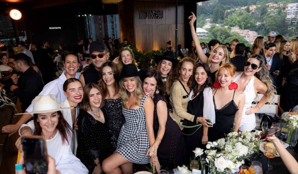 Un grupo numeroso de personas sonrientes posando para una foto grupal en el rooftop del Binn Hotel.