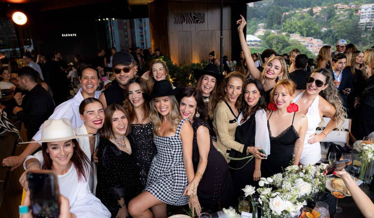 Un grupo numeroso de personas sonrientes posando para una foto grupal en el rooftop del Binn Hotel.