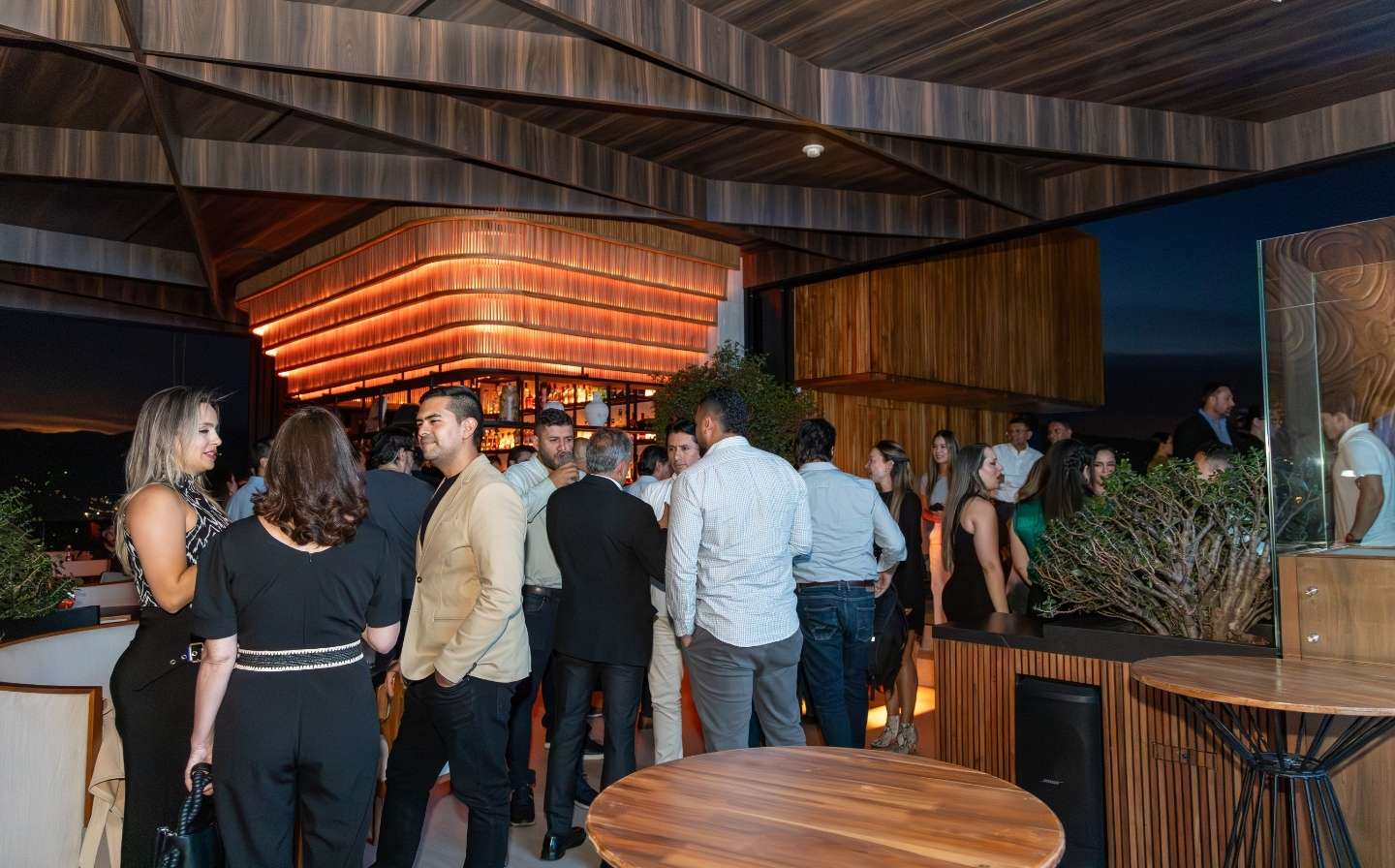 A group of people gathered around a bar and table, enjoying the evening, in the perfect spot for Binn Hotel: the boutique space for executive meetings.