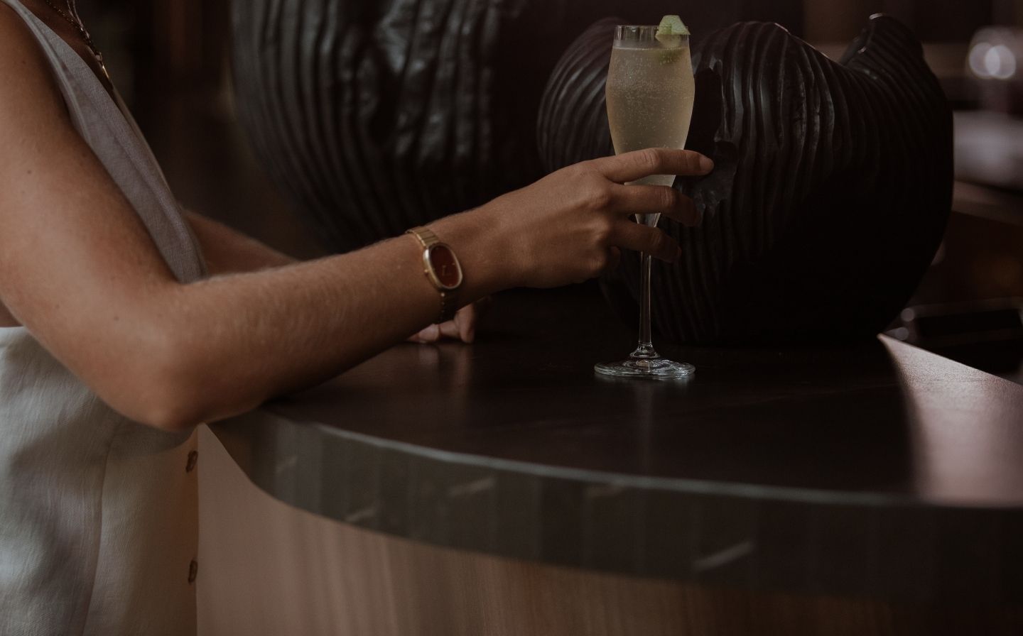 Mujer en un bar, levantando una copa de champán con experiencia.