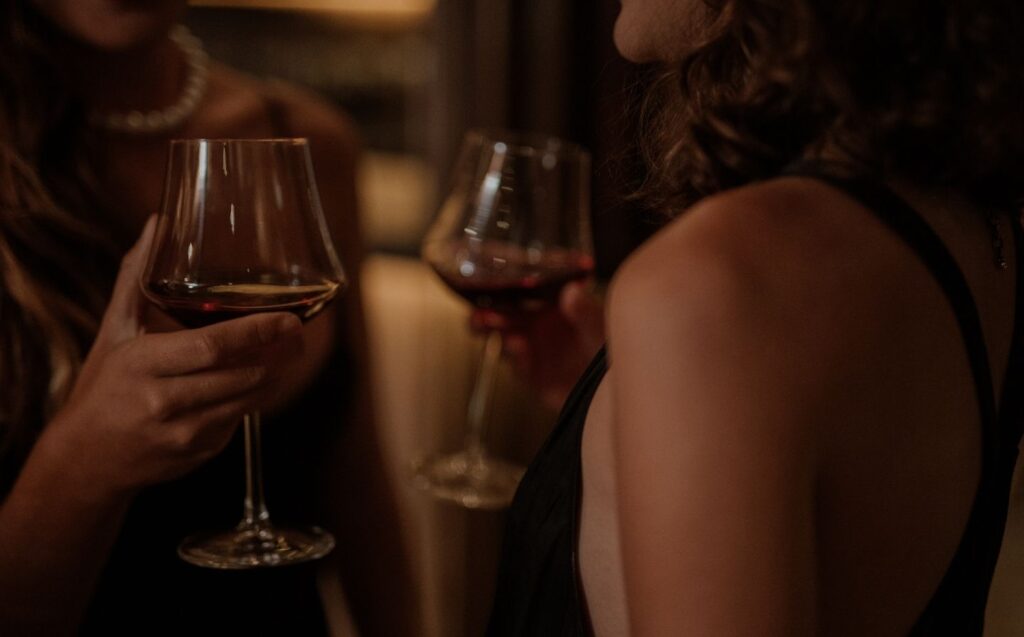 Dos mujeres sonrientes sosteniendo copas de auténtico Maridaj en una habitación acogedora