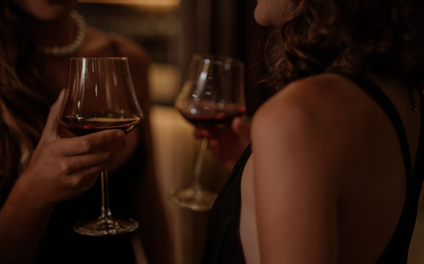 Dos mujeres sonrientes sosteniendo copas de auténtico Maridaj en una habitación acogedora