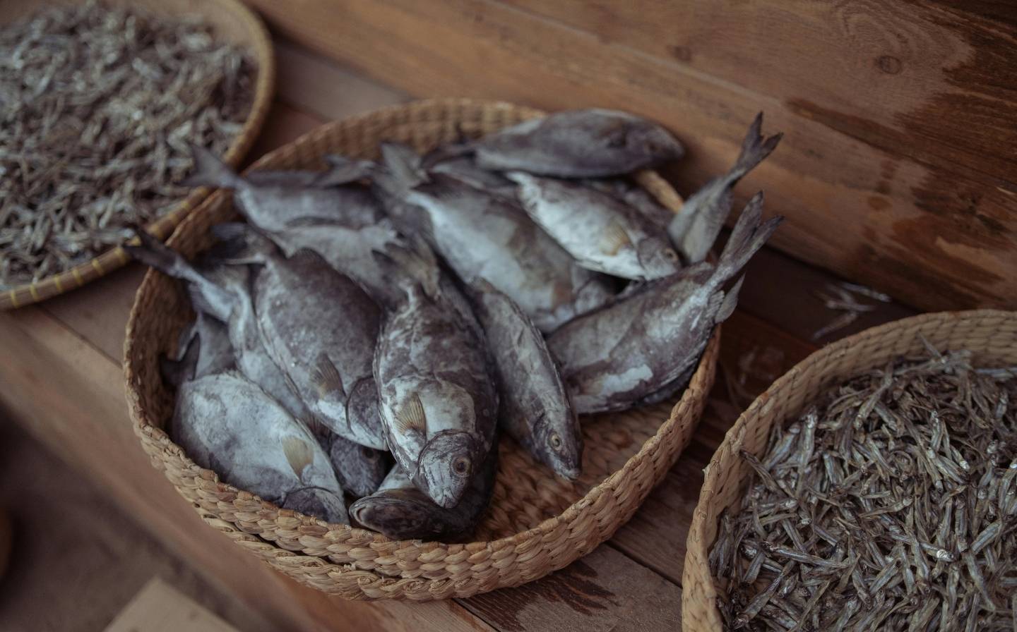 Una cesta de pescado seco sobre una mesa de madera, mostrando un color marrón y textura arrugada, representando la pesca del día reinventada en La Makha.