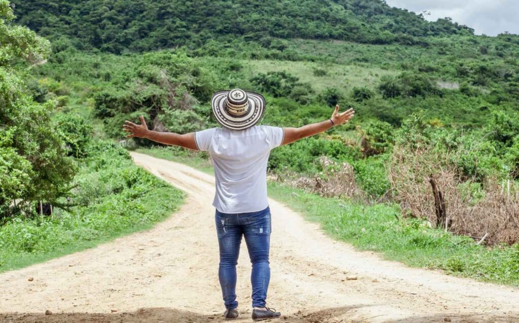 Hombre de pie en un origen camino de tierra, con los brazos abiertos, expresando alegría y conexión tecnica con el entorno