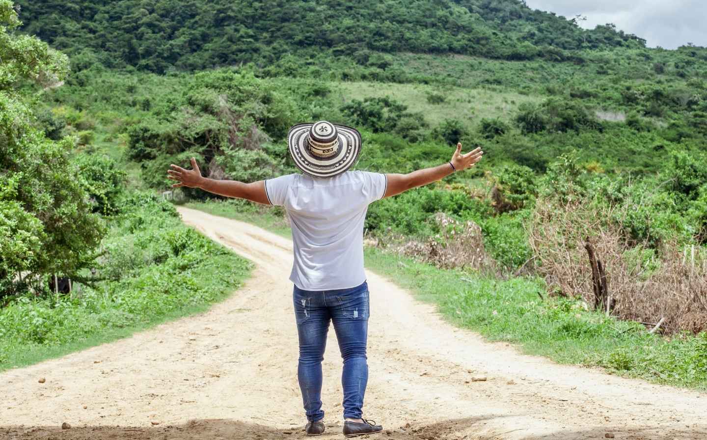 Hombre de pie en un origen camino de tierra, con los brazos abiertos, expresando alegría y conexión tecnica con el entorno