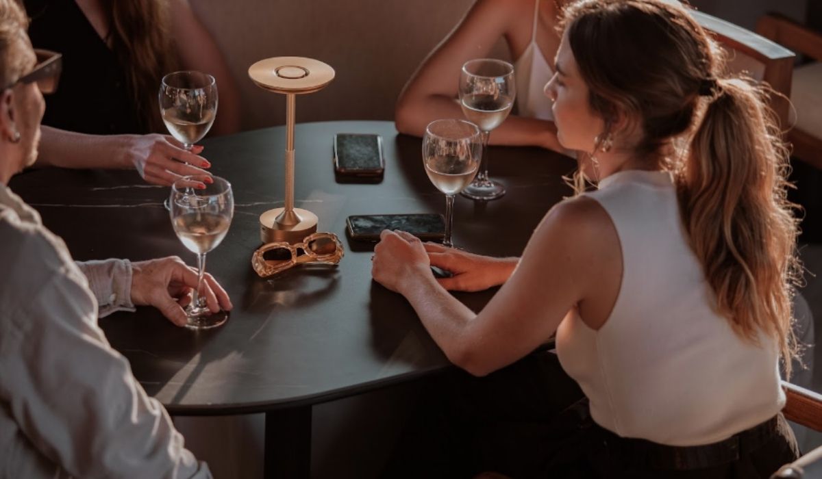 Three people sitting at a table, enjoying glasses of wine.