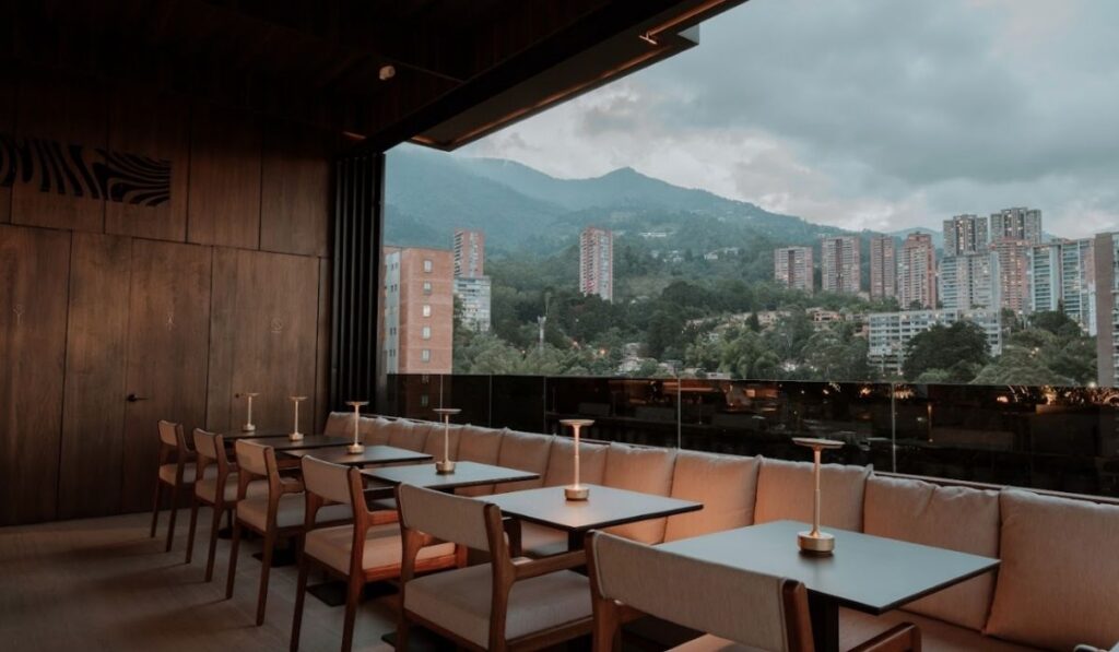 A restaurant featuring a scenic view of mountains alongside a vibrant city skyline