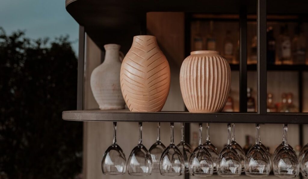 Barra con copas de vino y jarrones decorativos, creando un ambiente elegante y acogedor.