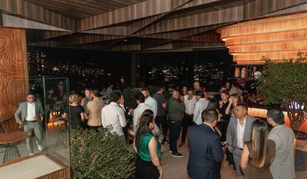 Several people standing around a bar, enjoying each other's company.