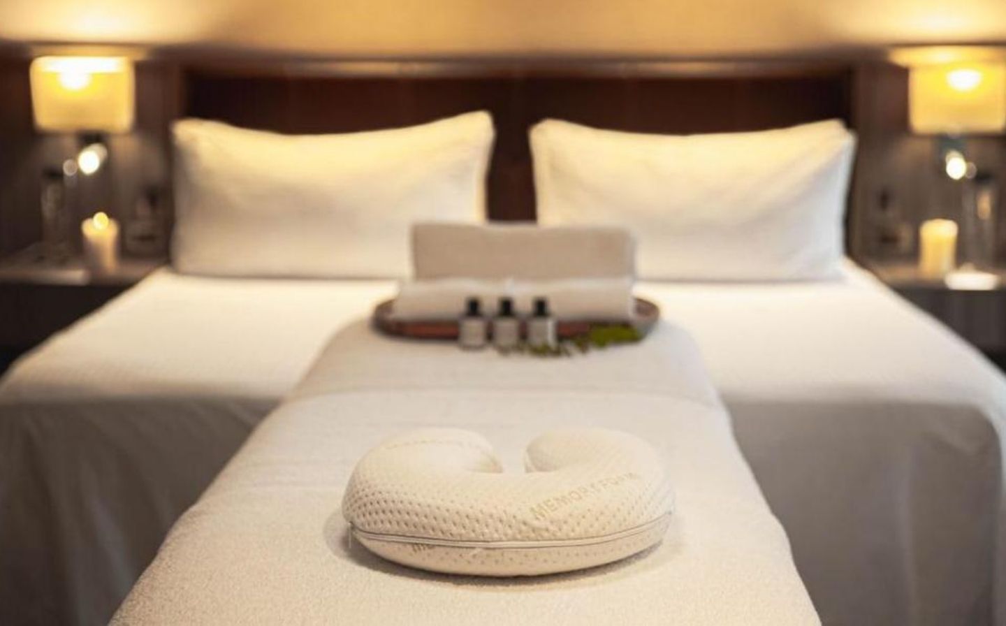 Cama con dos toallas blancas dobladas sobre ella, lista para usar este spa de lujo