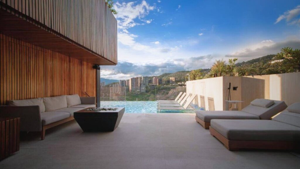 Área de descanso moderna junto a la piscina, con paredes de madera y vista a las montañas, ideal para brunch en Etro Rooftop