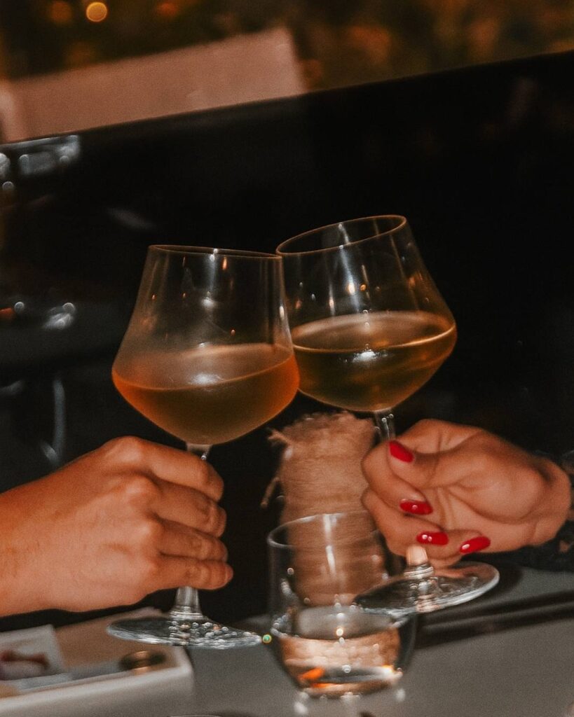 Two people toasting with wine glasses under the stars, enjoying a romantic dinner at Etro.
