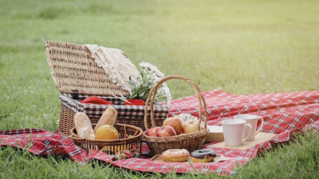 Picnic basket with bread, coffee, and fruit on the grass, ideal for enjoying luxurious experiences in Antioquia.