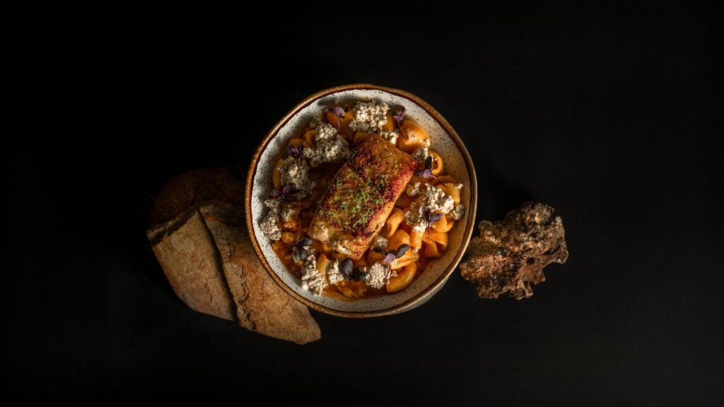 Un plato de comida fresca sobre una mesa negra, representando la filosofía de "De la pesca local al plato" en La Makha