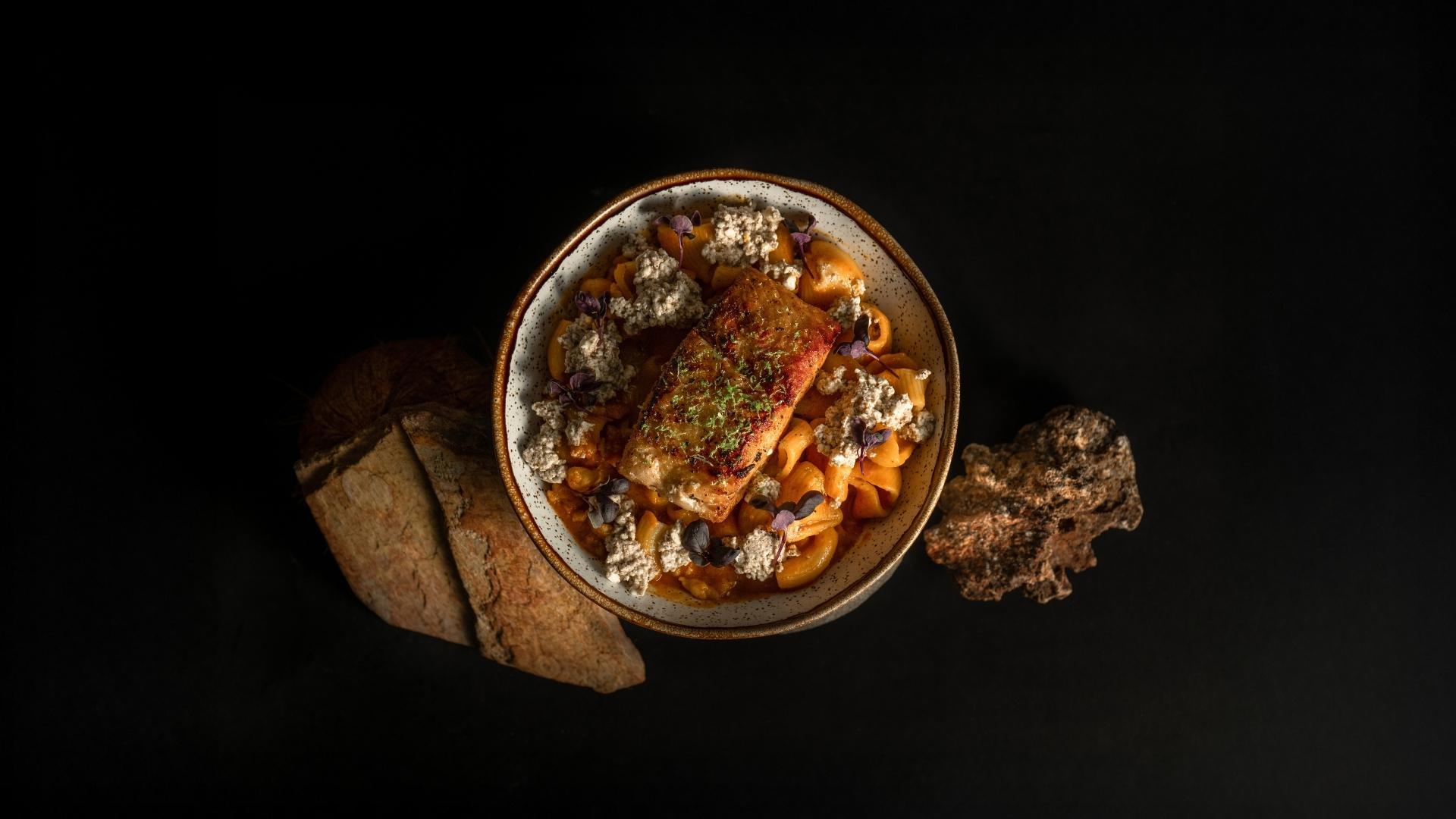 Un plato de comida fresca sobre una mesa negra, representando la filosofía de "De la pesca local al plato" en La Makha