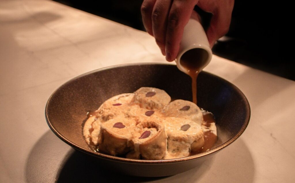 Persona vertiendo jarabe sobre un bol de helado, simbolizando la fusión de sabores en La Makha