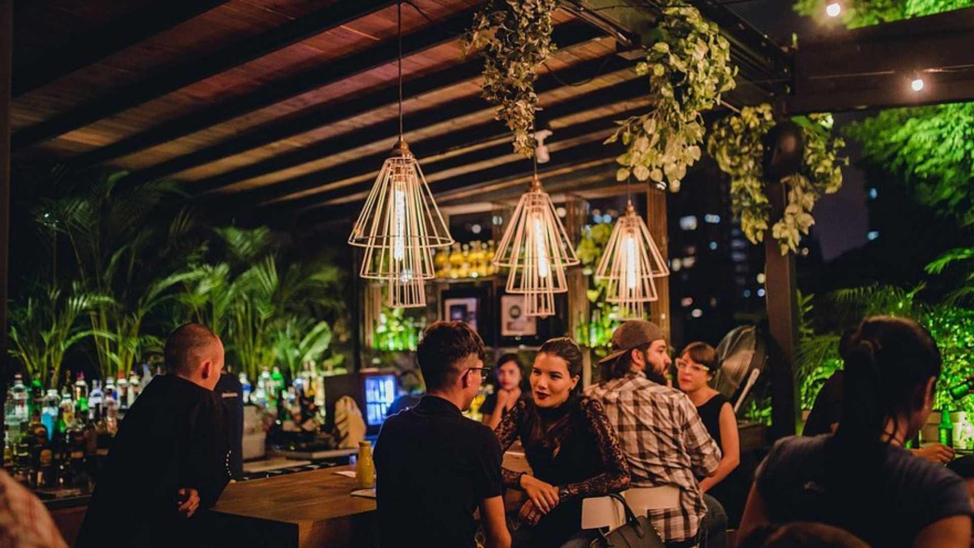 People enjoying a night out at a brightly lit bar on Medellín's exclusive rooftops