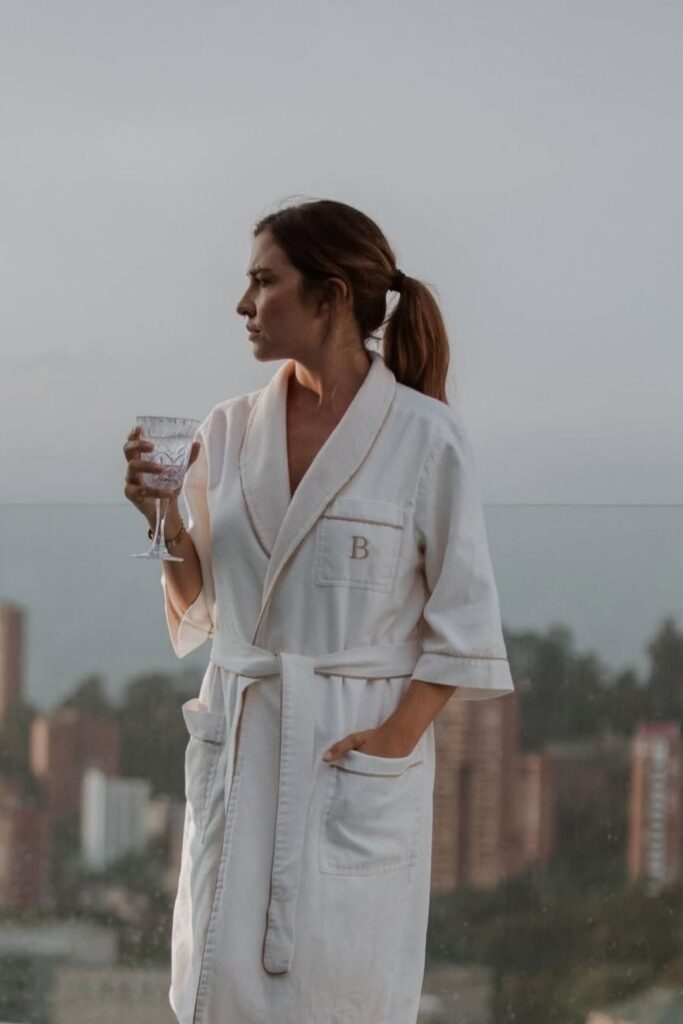 Mujer en bata sosteniendo una copa de vino, disfrutando de un momento de relajación en actividades wellness en Medellín