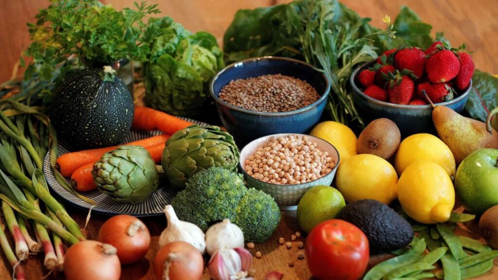 Variedad de frutas y verduras frescas dispuestas en una mesa, destacando la producción responsable y el apoyo a los productores