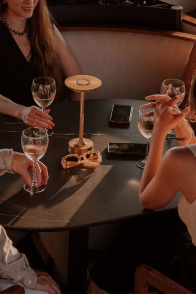 Tres personas sentadas en una mesa, disfrutando de copas de vino durante una sesión de atardecer