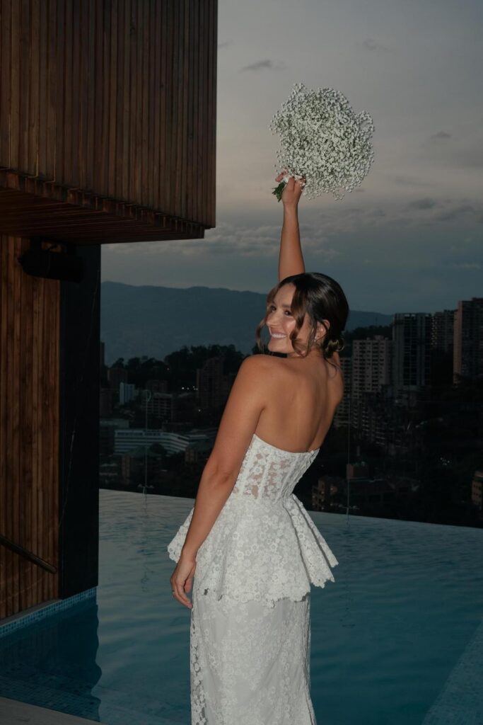 Novia levantando su ramo al atardecer en Medellín, con un fondo de colores cálidos y románticos.