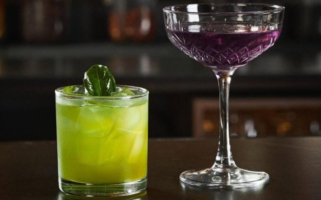 Dos cócteles caseros de La Makha sobre la barra, decorados con una hoja verde fresca.