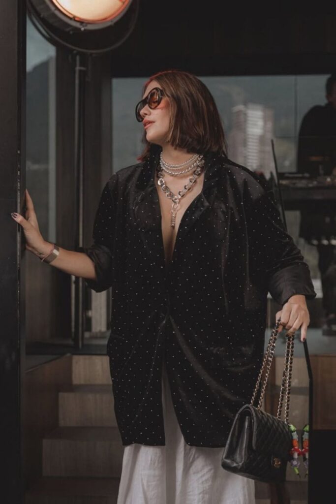 Mujer con chaqueta de terciopelo negro y pantalones blancos, lista para visitar Etro con estilo