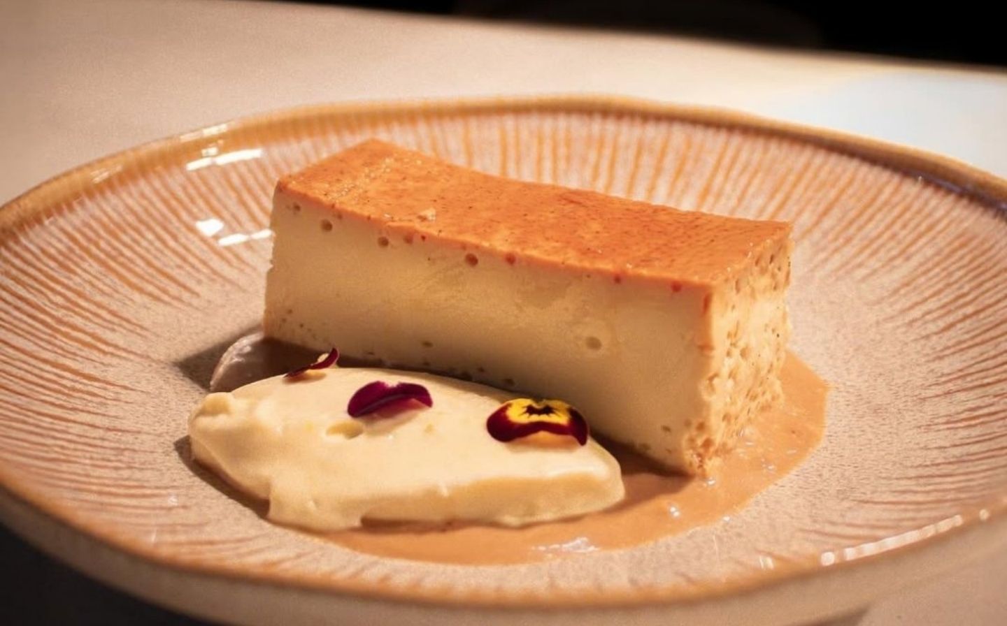 Un trozo de cheesecake cremoso sobre un plato blanco, listo para disfrutar con la playlist perfecta de La Makha