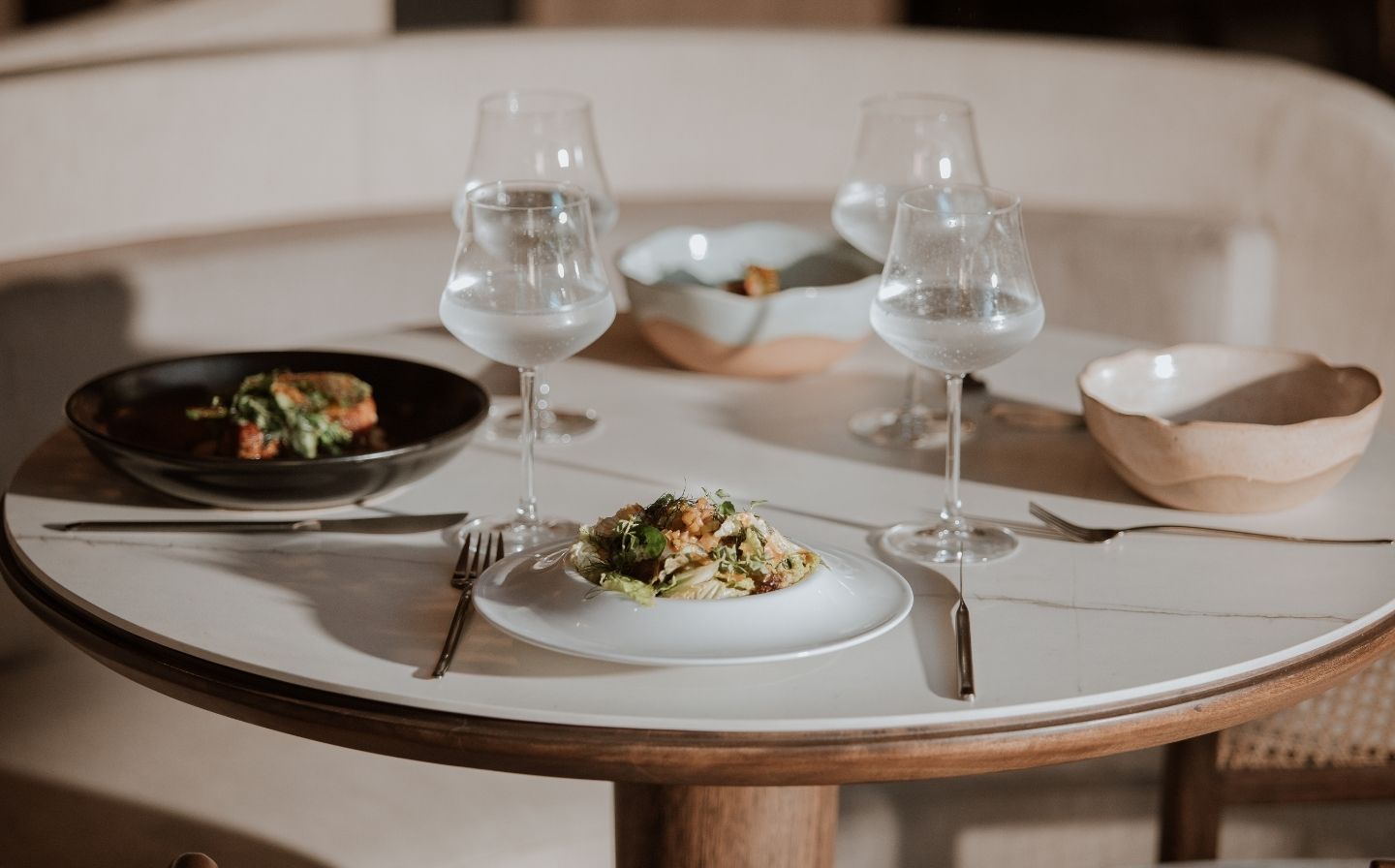 A table set with two elegant plates and glasses, showcasing luxury dining plans in Medellín