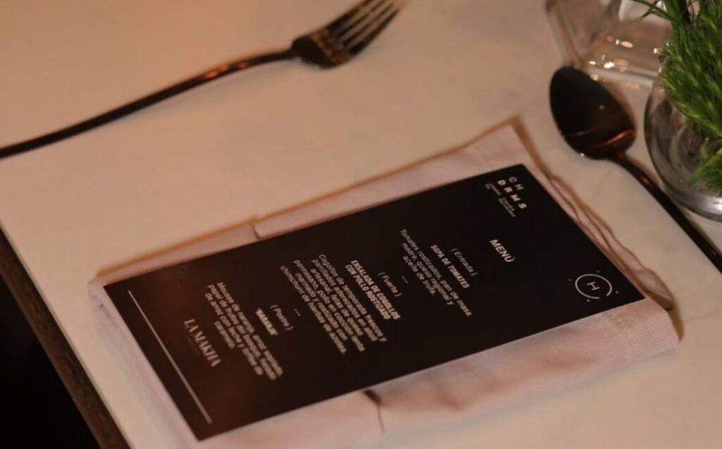 Menú de boda de lujo sobre una mesa, acompañado de un tenedor y un cuchillo elegantes