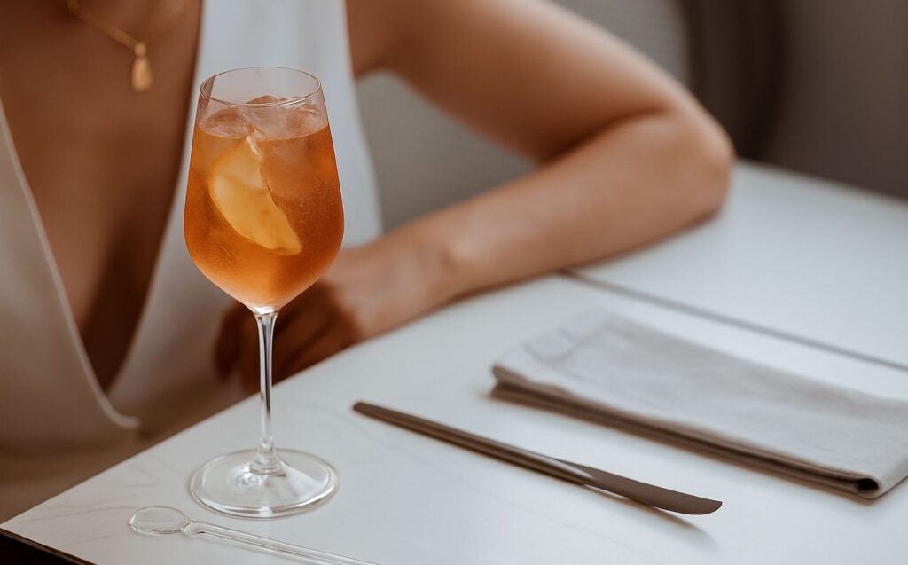 Mujer sentada en una mesa, disfrutando de una copa de vino, en un ambiente de mixología colombiana elevada