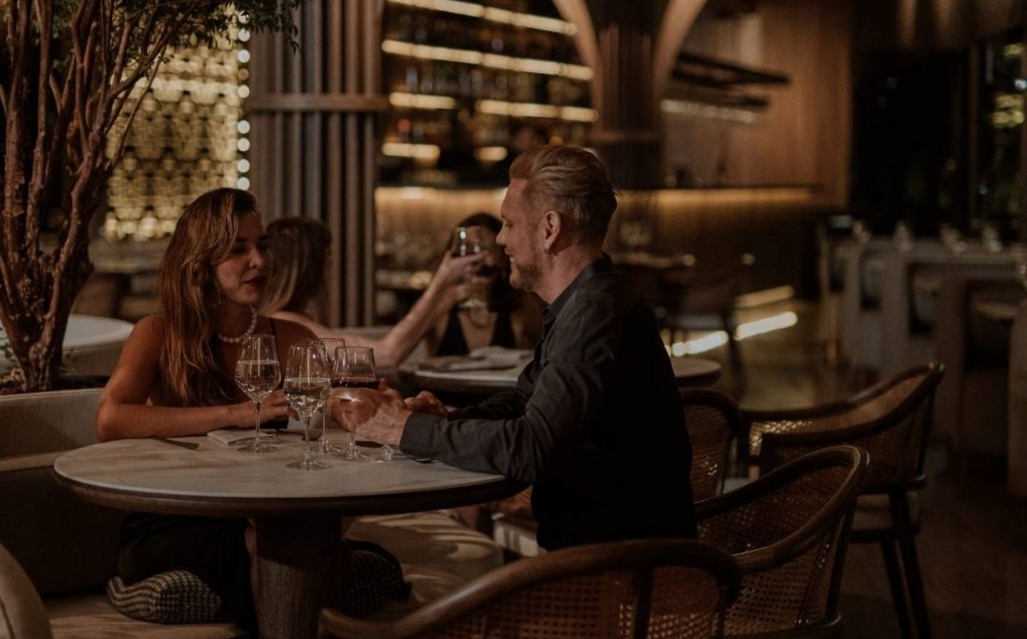 Pareja sentada en una mesa de restaurante, disfrutando de una cena romántica en Medellín