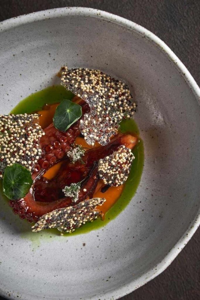 Un tazón blanco con salsa verde y carne, representando sabores gourmet en Medellín