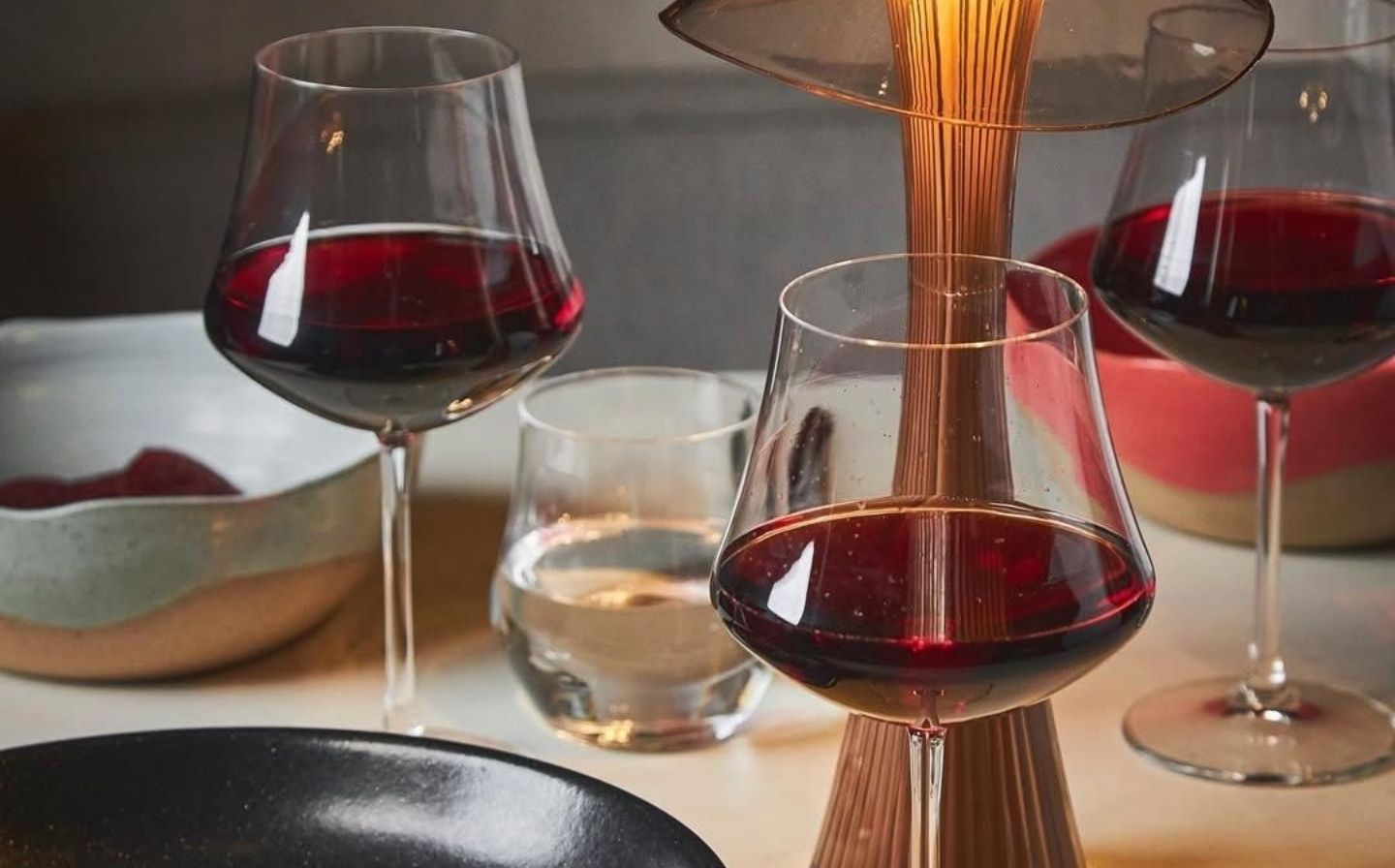 Tres copas de vino tinto sobre una mesa, reflejando la experiencia gourmet en Medellín.