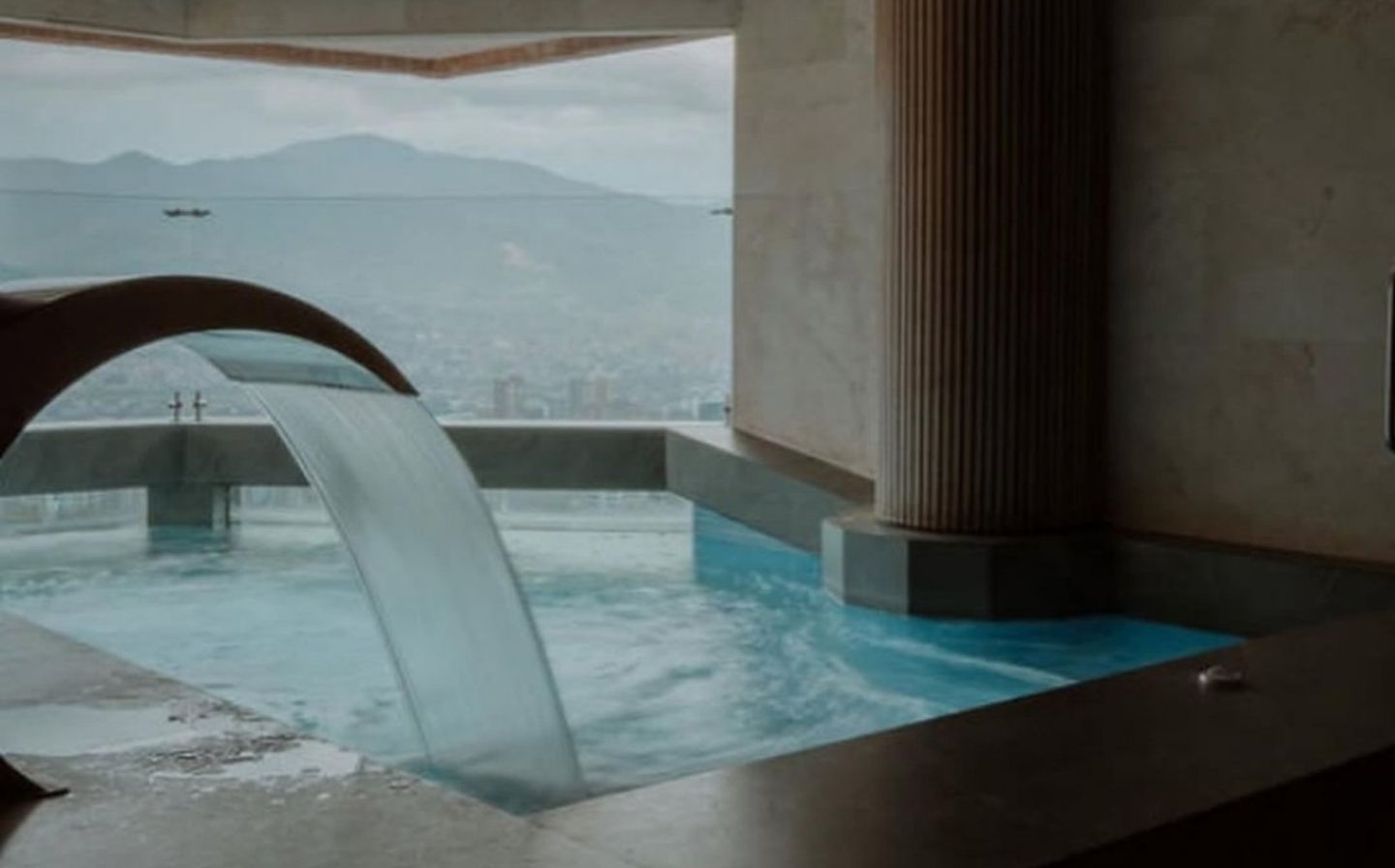 Cascada en un baño del hotel BINN, con vistas a las montañas, creando un ambiente de spa de lujo