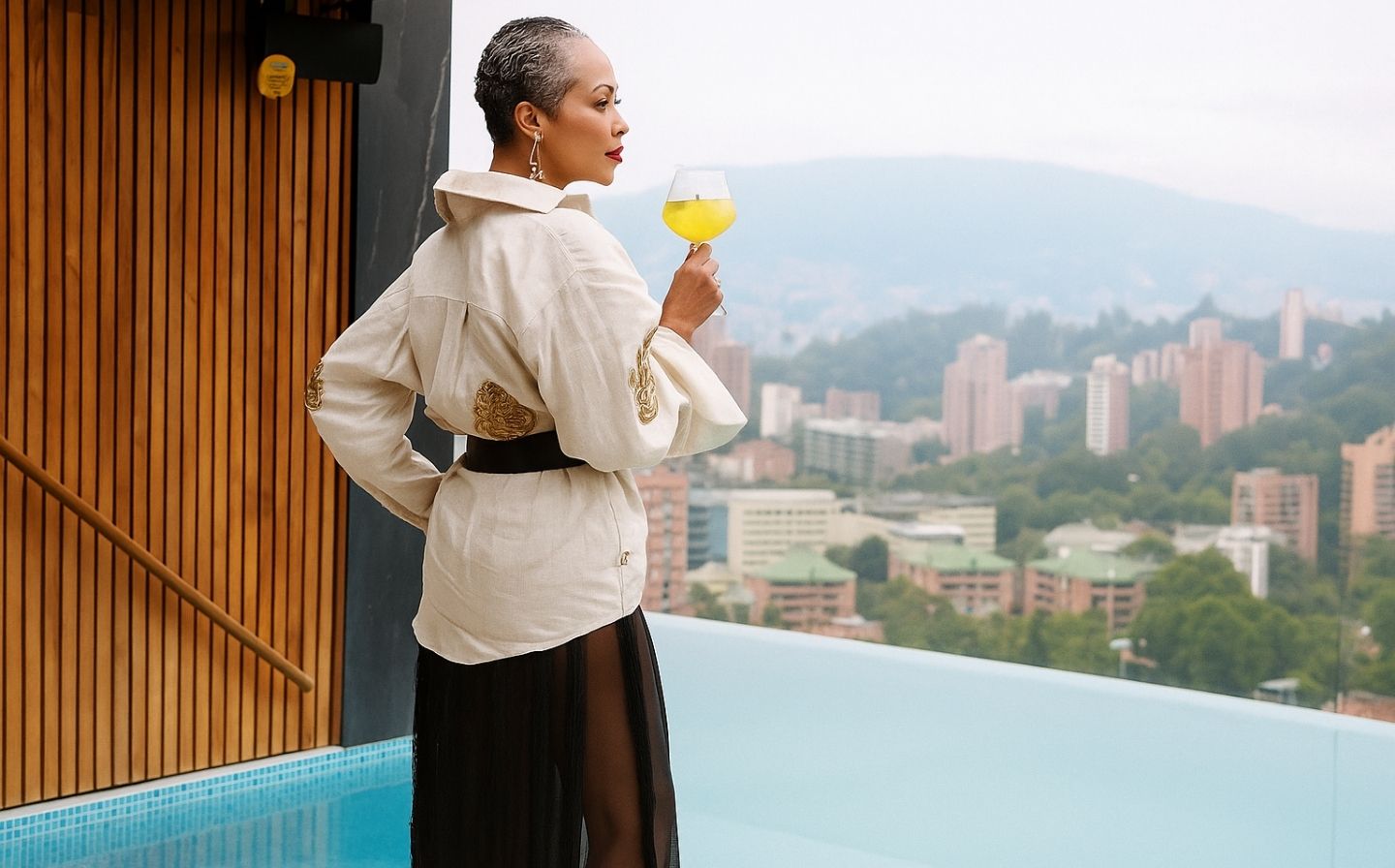 Mujer en bata blanca sosteniendo una copa de vino durante el atardecer en una sesión de afterwork.