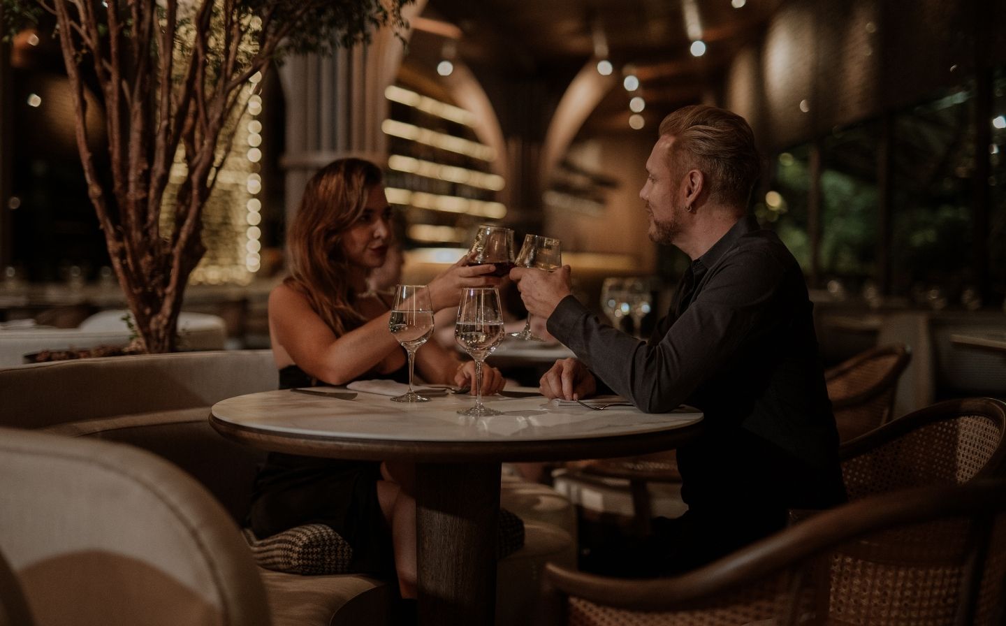 Dos personas levantando copas de vino en un restaurante lujoso de Medellín