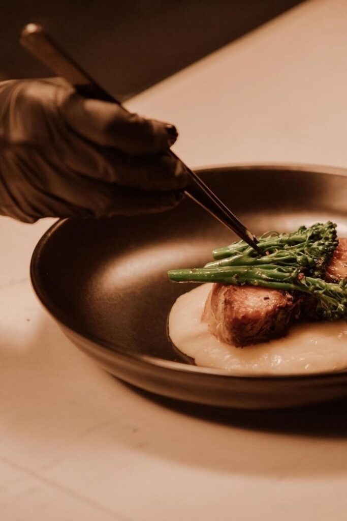 A dish with a piece of meat and broccoli, presented at the event "A Day with Chef David Suárez Estrada"