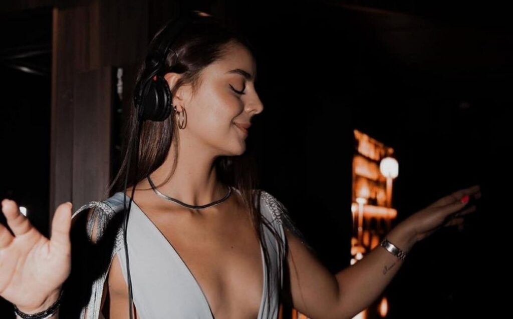 Mujer con vestido blanco bailando y usando auriculares en una noche de Etro, narrada por un influencer