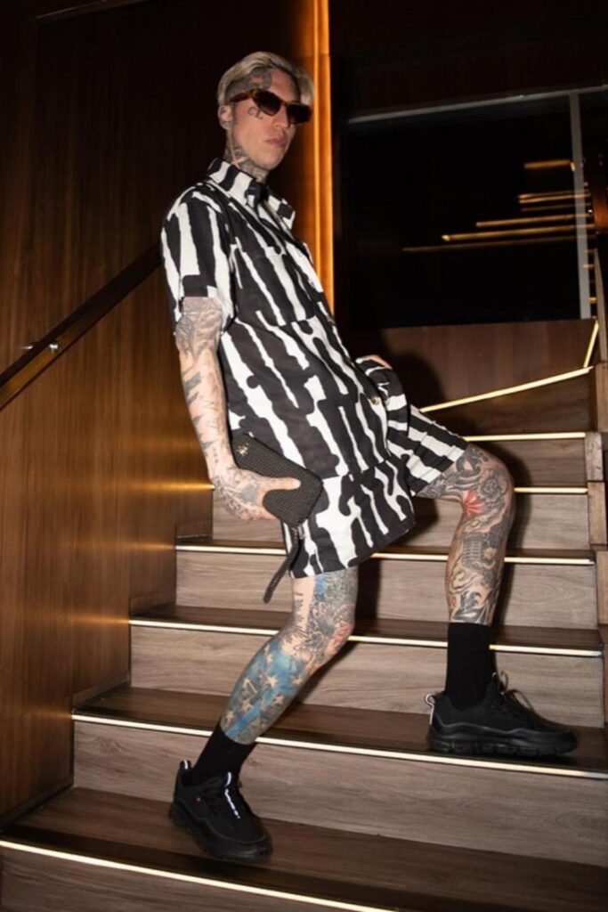 Hombre tatuado en las piernas, de pie en unas escaleras, durante una noche en Etro, narrada por un influencer