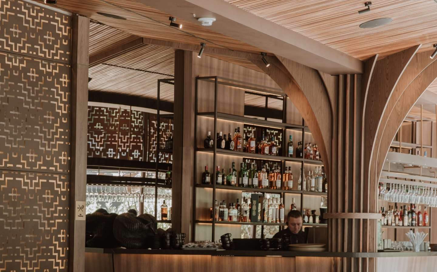 Bar con estanterías de madera y un mostrador, invitando a disfrutar de la experiencia completa de La Makha
