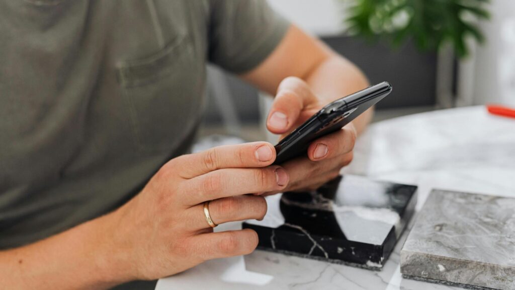 Un hombre sentado en una mesa usa su celular, explorando la nueva carta de La Makha