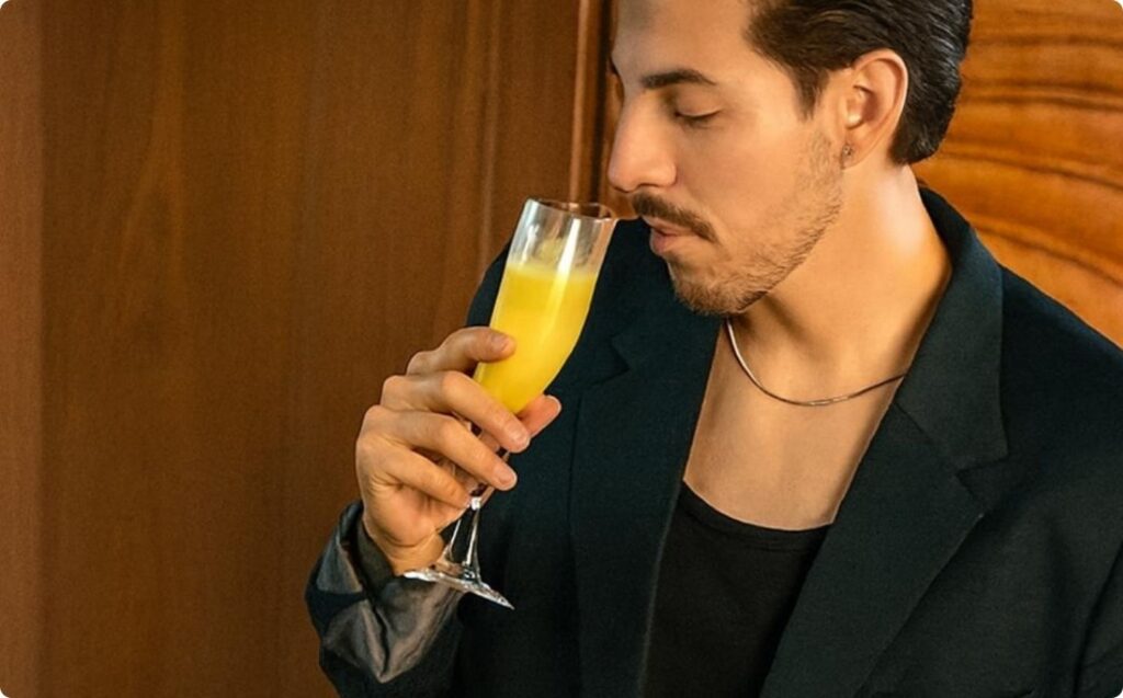 Hombre de traje sosteniendo un vaso de jugo de naranja