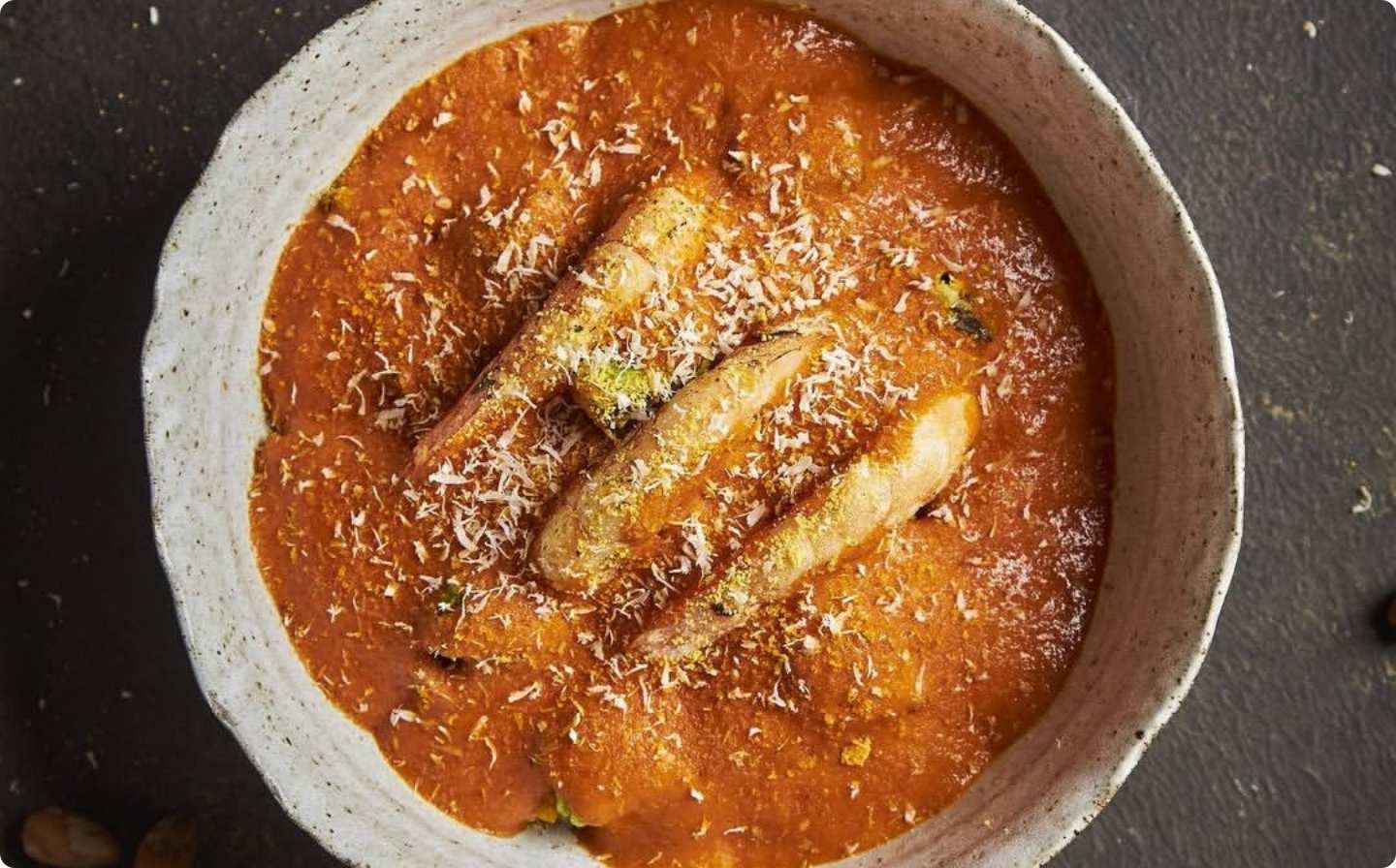 Un tazón de salsa de tomate con queso y pescado.