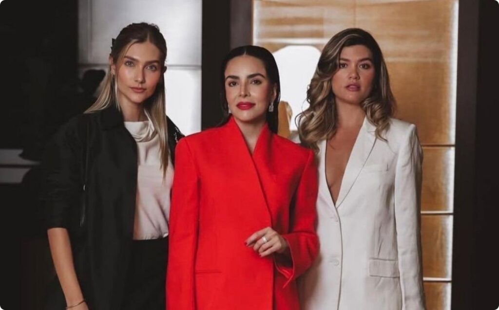 Tres mujeres vestidas con blazers de colores rojo, blanco y negro posando para una fotografía de moda o evento.